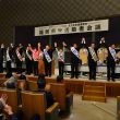 満場の拍手に応える（左から）田村、仁比両氏と10人の市議候補＝7日、北九州市