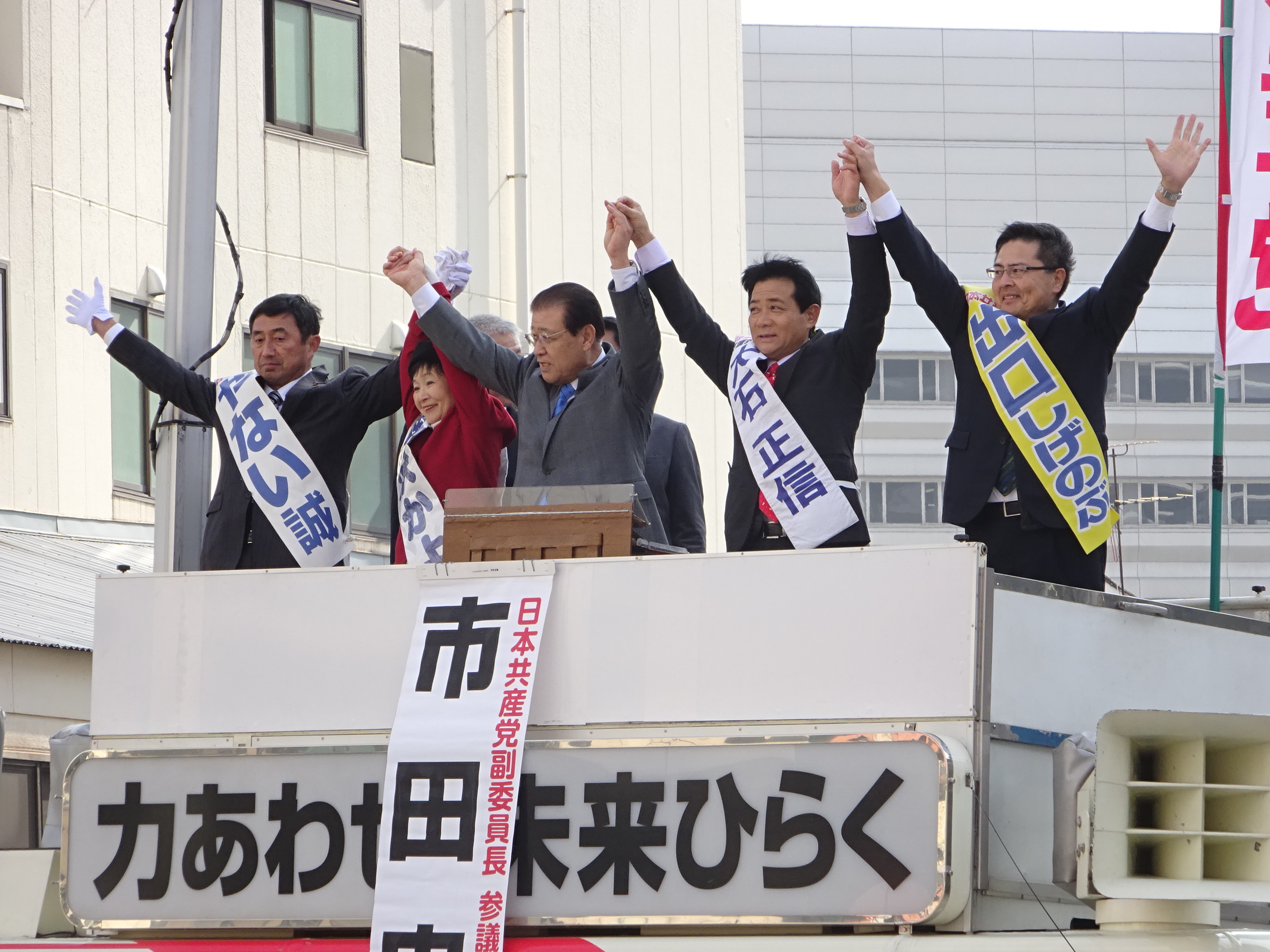 拍手に手をあげてこたえる（左から）やない、藤沢、市田、大石、出口各氏＝２１日、北九州市