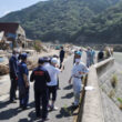 かさ上げした堤防を乗り越えて水が押し寄せた現場を確認する調査団＝２日、熊本県八代市坂本町