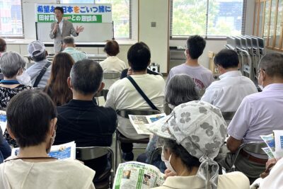 田村氏（奥）の話に聞き入る参加者たち＝６月３０日、宮崎県日南市