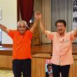 拍手に応える田村氏（右）と良岡予定候補（左）＝２５日、鹿児島県喜界町