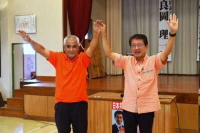 拍手に応える田村氏（右）と良岡予定候補（左）＝２５日、鹿児島県喜界町