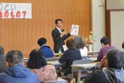 資料を使い話す田村氏（中央）＝６日、福岡県久留米市