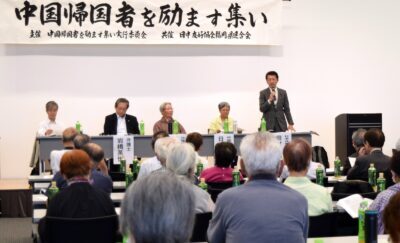 報告をする田村氏（壇上右側）＝１日、福岡市