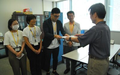 要望書を手渡す山野氏たちと田村氏（奥右) =28日、福岡市