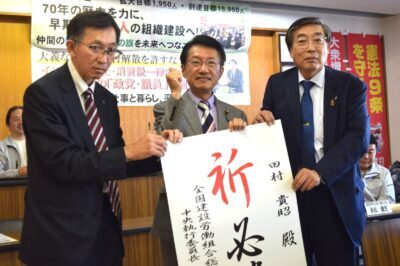 為書きを受け取る田村氏（真ん中）＝22日、福岡市南区