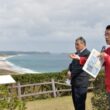 訓練が予定されている海浜公園（奥）を背に訓練中止を訴える（右から）田村、山内両氏＝１日、鹿児島県南種子町