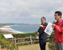 訓練が予定されている海浜公園（奥）を背に訓練中止を訴える（右から）田村、山内両氏＝１日、鹿児島県南種子町