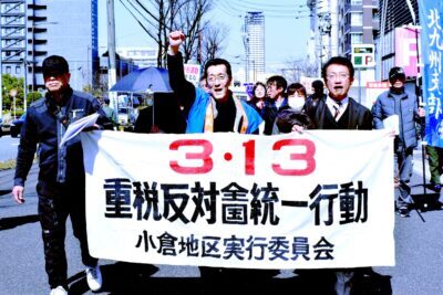 参加者とともにデモ行進する田村氏（前列右端）＝１１日、北九州市小倉北区
